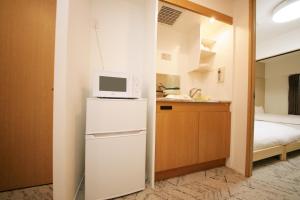 una pequeña cocina con nevera y microondas en goom Hotel Fukuoka-Tenjin, en Fukuoka