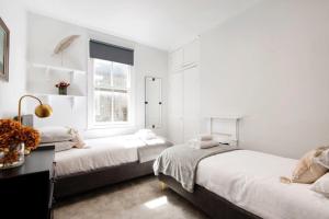 a white room with two beds and a window at Modern Family Home in London Close to Amenities and Train in London