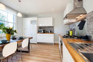a kitchen with white cabinets and a table and chairs at Modern Family Home in London Close to Amenities and Train in London