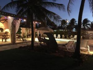 a person sitting in chairs next to a pool at night at Villa Bianca Suítes in Beberibe