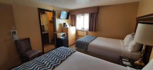 a hotel room with two beds and a chair at Travelodge by Wyndham Kanab in Kanab