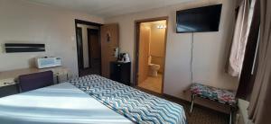 a room with a bed and a desk and a television at Travelodge by Wyndham Kanab in Kanab