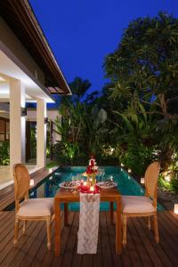 a table and chairs on a deck next to a pool at Villa Sally in Canggu