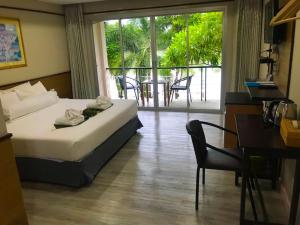 a bedroom with a bed and a desk and a balcony at Nopparat Garden in Samut Songkhram