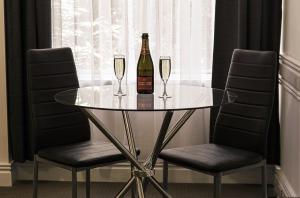 a glass table with two glasses and a bottle of wine at Melbourne Kew Central Apartments Official in Melbourne