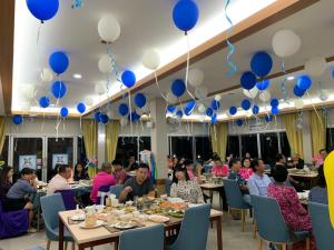 a group of people sitting at tables with blue and white balloons at Nopparat Garden in Samut Songkhram