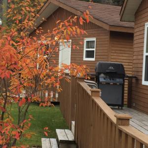 a bbq grill on a deck next to a house at Middle Brook Cottages & Chalets in Glenburnie