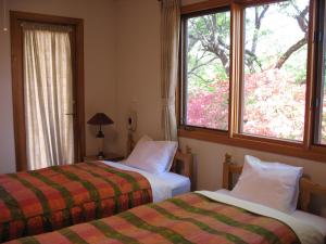 2 camas en una habitación con ventana en B&Bペンション Second House Plus en Nikko