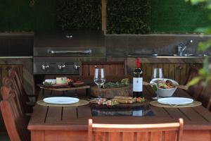 a table with a bottle of wine and wine glasses at Lazy Acre Log Cabins in Lakes Entrance