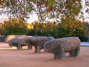 um grupo de estátuas de ovelhas de pedra em um parque em Toros de Guisando em El Tiemblo