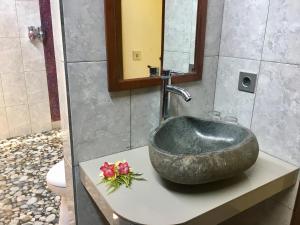 a bathroom with a stone sink with flowers on a counter at Nusa Garden Homestay in Nusa Lembongan