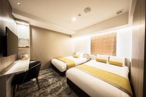 a hotel room with two beds and a television at The Rise Osaka Kitashinchi in Osaka