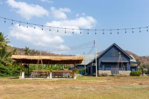 um pavilhão com mesas e cadeiras em frente a uma casa em The Barn Hua Hin em Khao Tao