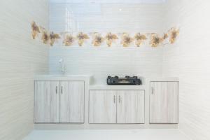 a white kitchen with a sink and a stove at RedDoorz Syariah near Tanjung Pinang City Center in Tanjung Pinang 