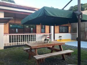 a picnic table with an umbrella in front of a building at Mayumi Lodge in Puerto Princesa City