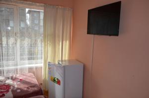 a small white refrigerator in a room with a window at Hotel Kezdesu in Almaty