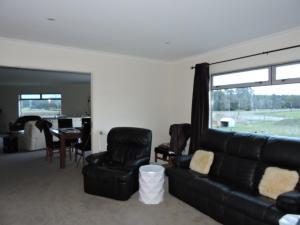 a living room with a black leather couch and chairs at 5 Acres B&B in Tokoroa