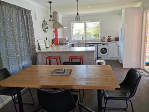 Kerikeri Sunny Modern 2 Bedroom Apartments في كيريكيري: مطبخ وغرفة طعام مع طاولة وكراسي خشبية