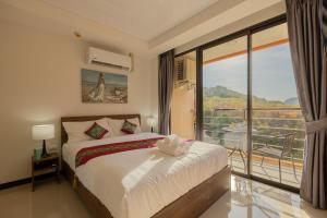 a bedroom with a bed and a large window at NaiHarn Sea Condo by Holy Cow, 1-BR, mountain view in Nai Harn Beach +31 photos