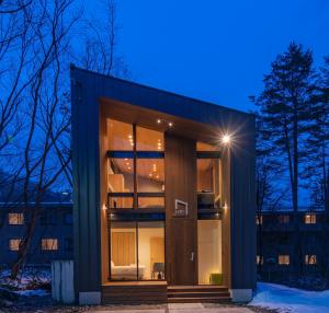 una casa con una gran puerta de cristal por la noche en Kairos by the Mountain by The Hakuba Collection en Hakuba