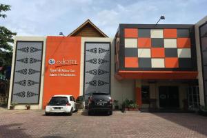 two cars parked in a parking lot in front of a building at Edotel Syariah Nilam Sari Mitra RedDoorz in Pekanbaru