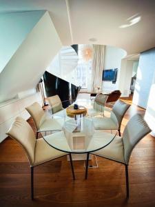 een woonkamer met een glazen tafel en stoelen bij The Crown Penthouse Bahnhofstrasse in Zürich