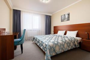 a hotel room with a bed and a desk and a table and chair at Continent Hotel in Stavropol