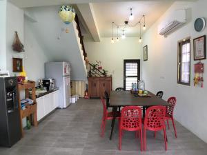 a kitchen with a dining room table and red chairs at JOY Homestay in Shoufeng