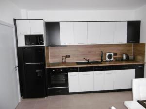 a kitchen with white cabinets and a black refrigerator at Апартамент Жекови in Tsarevo