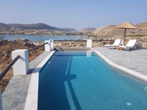 a blue swimming pool with a view of the water at VILLA ALEXANDROS in Naousa