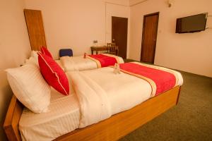 een slaapkamer met 2 bedden met rode en witte kussens bij OYO 135 Lost Garden Apartment and Guest House in Kathmandu