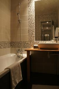La salle de bains est pourvue d'une baignoire, d'un lavabo et d'un miroir. dans l'établissement Hôtel et Restaurant Le Regina, au Puy-en-Velay