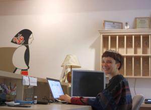 Ein junger Mann, der an einem Schreibtisch mit einem Laptop sitzt. in der Unterkunft Retro Hostel in Cluj-Napoca