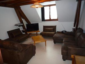 a living room with leather furniture and a tv at Gîte Les Baudy in Servance