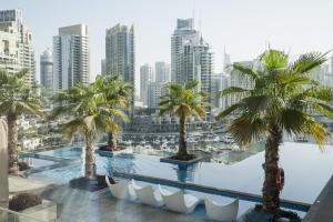 a pool with palm trees and a city at GuestReady - Cactus Bloom Marina Gate in Dubai