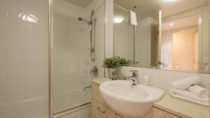 y baño blanco con lavabo y ducha. en Inn on the Park Apartments en Brisbane