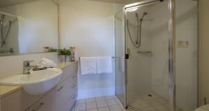 a white bathroom with a shower and a sink at Inn on the Park Apartments in Brisbane