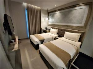 a hotel room with two beds and a flat screen tv at Savero Style Bogor in Bogor