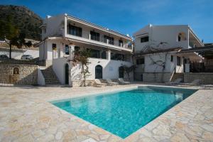 a villa with a swimming pool in front of a house at Velanidia Apartments in Plataria