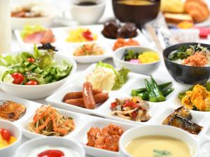 APA Hotel Hitachinaka Katsuta Station في هيتاتشي-ناكا: طاولة عليها العديد من أطباق الطعام
