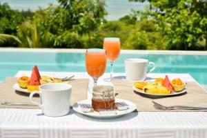 a table with two glasses of juice and plates of fruit at The Palm Residence by Amazing Zanzibar in Chanjani