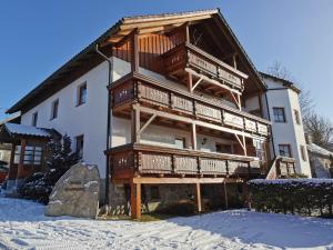 a large building with wooden balconies in the snow at Ferienhaus-Haidweg-Wohnung-1 in Haidmühle