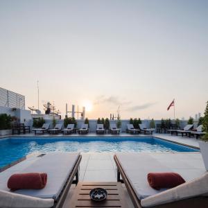a pool on the roof of a building with lounge chairs at The Mulberry Bangkok Khaosan Road in Bangkok