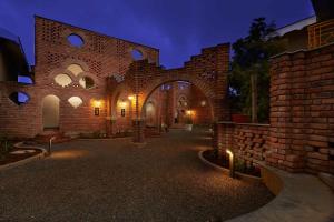 un grand bâtiment en briques avec une arche la nuit dans l'établissement Saj By The Lake, Malshej Ghat, à Malshej Ghat