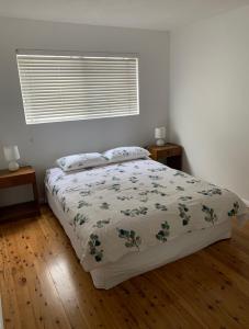 a bedroom with a bed with a comforter and a window at 2 Bed Bar Beach Apartment - stroll to beach & cafes, supermarket apartment number 6 in Newcastle