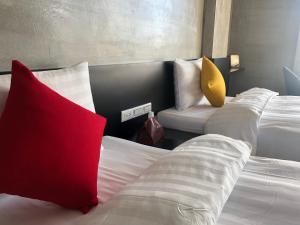 a hotel room with three beds with red and yellow pillows at SH Villa in Huxi