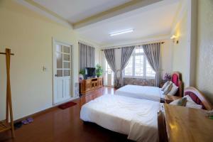 a bedroom with a white bed and a large window at The One Home Đà Lạt in Da Lat