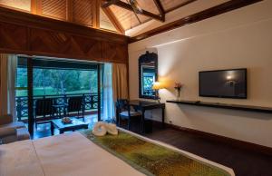 ein Schlafzimmer mit einem Bett, einem Schreibtisch und einem Fernseher in der Unterkunft Nexus Resort & Spa Karambunai in Kota Kinabalu
