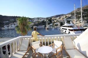 Un niño parado en un balcón con vistas al puerto deportivo en Limani Life, en Symi