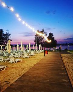 a boardwalk with chairs and lights on a beach at Firlej Plaża in Firlej